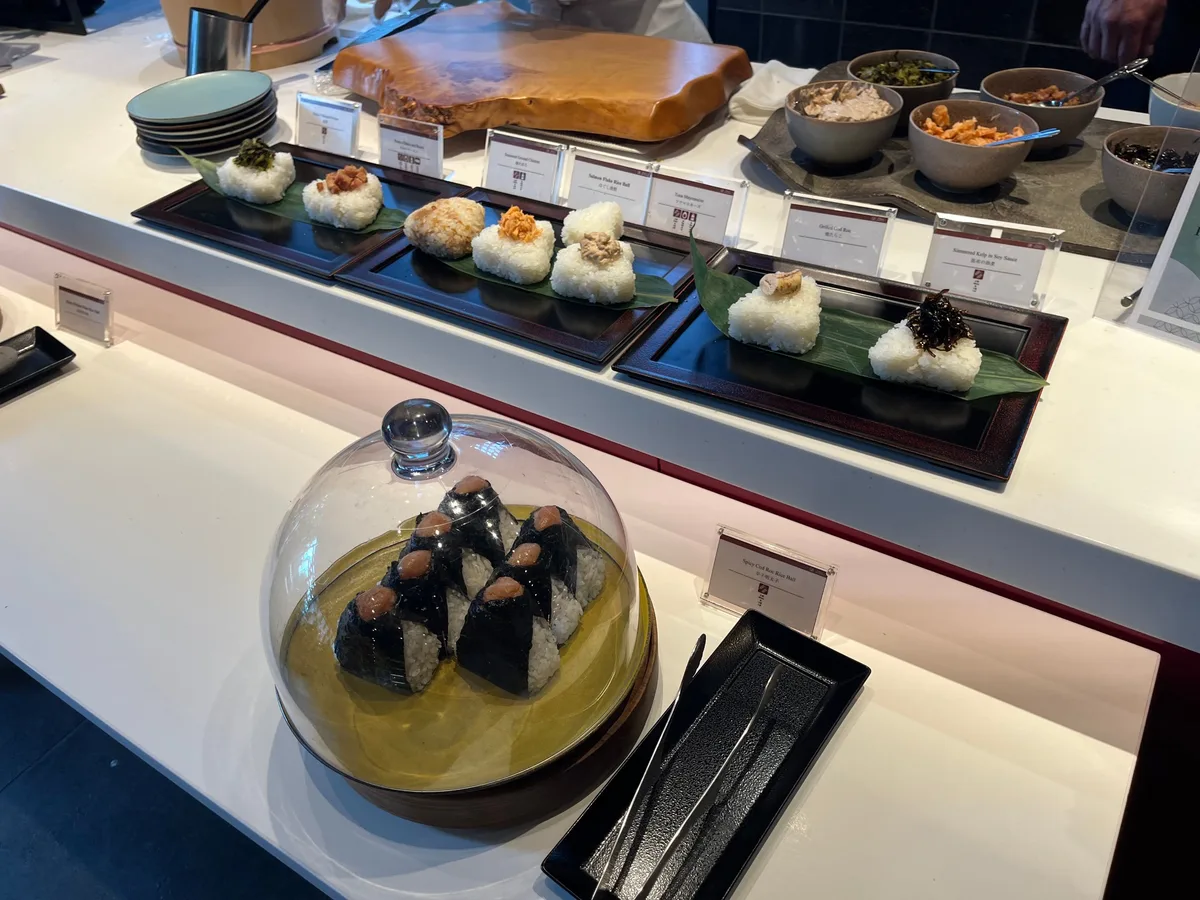 自助早餐區長盤上排列多款日式飯糰與配料小菜